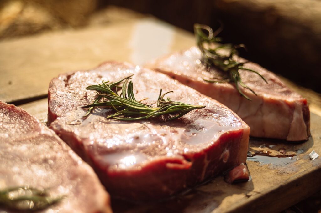 Dikke rauwe steaks met takjes rozemarijn op een houten plank